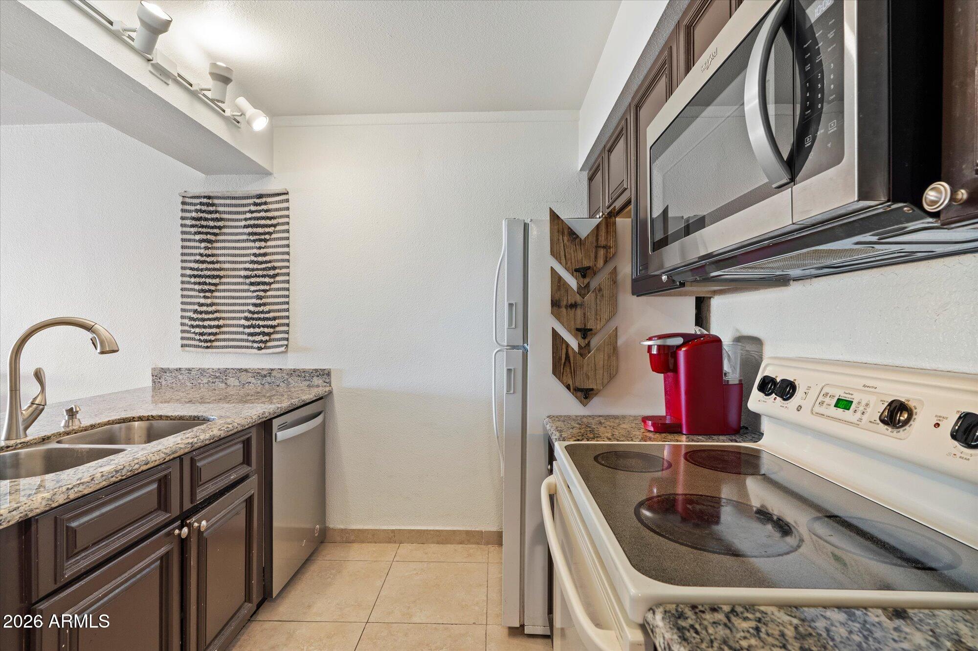 7625 East Camelback Road, Unit B325 Scottsdale, AZ 85251 - Photo 4 of 24 a kitchen with stainless steel appliances granite countertop a sink and cabinets