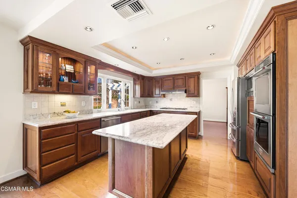 a kitchen with stainless steel appliances granite countertop a kitchen island a stove a sink and a refrigerator