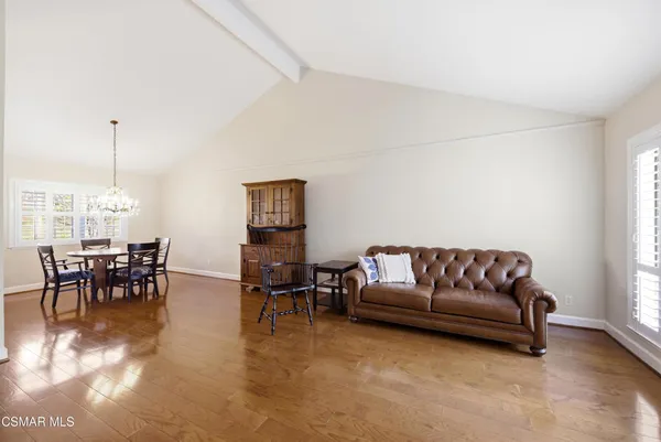 a living room with furniture and a dining table with chandelier