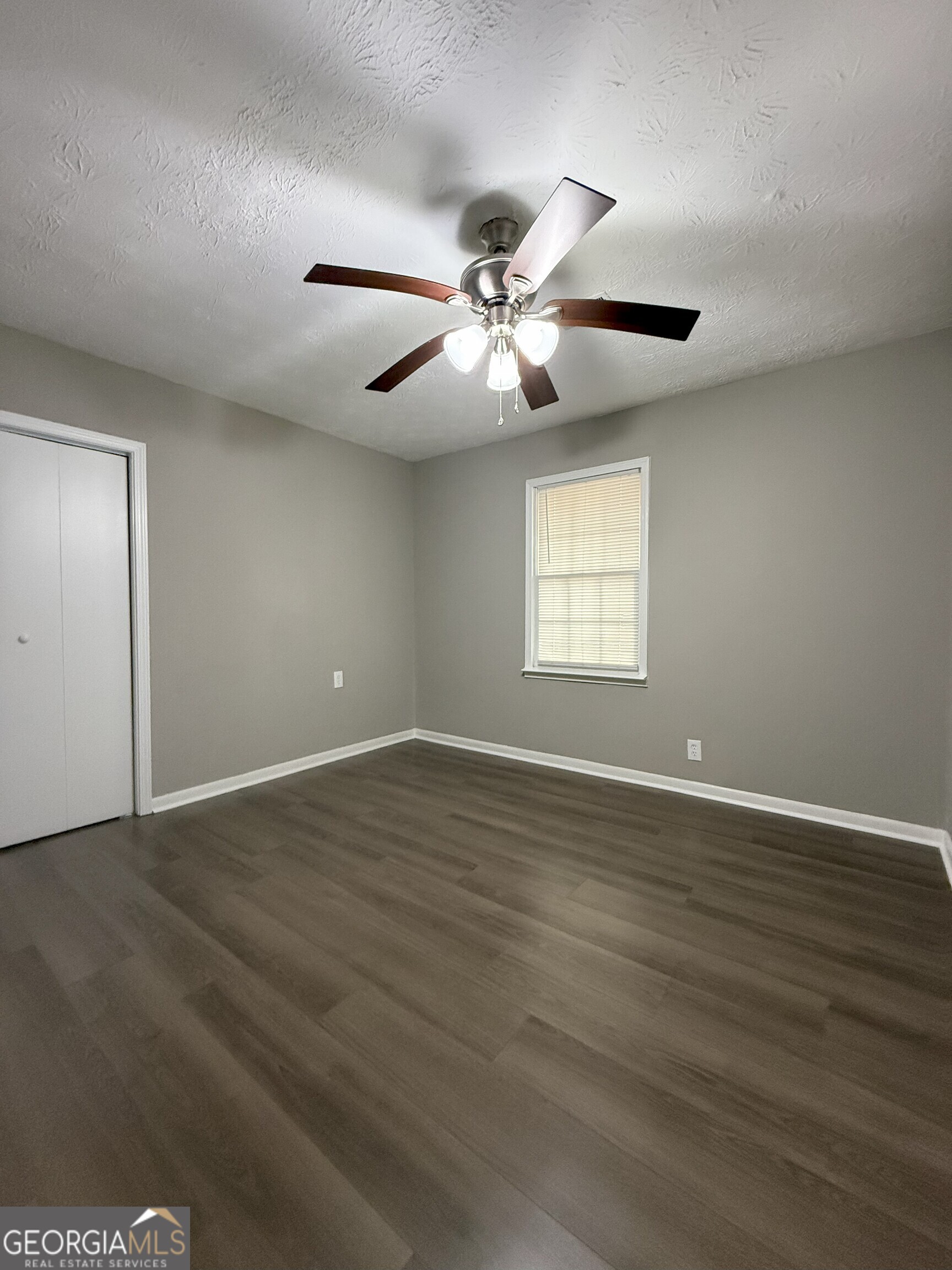 516 Harris Street Monroe, GA 30655 - Photo 13 of 25 a view of an empty room with wooden floor and a window