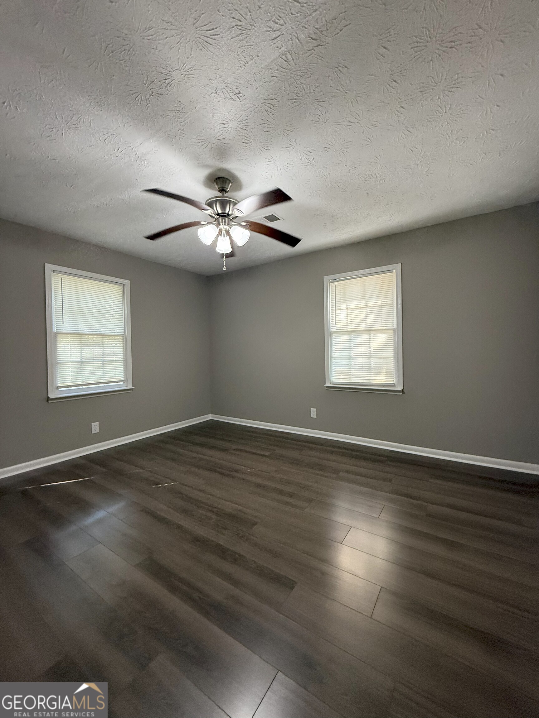 516 Harris Street Monroe, GA 30655 - Photo 14 of 25 a view of an empty room with wooden floor and a window