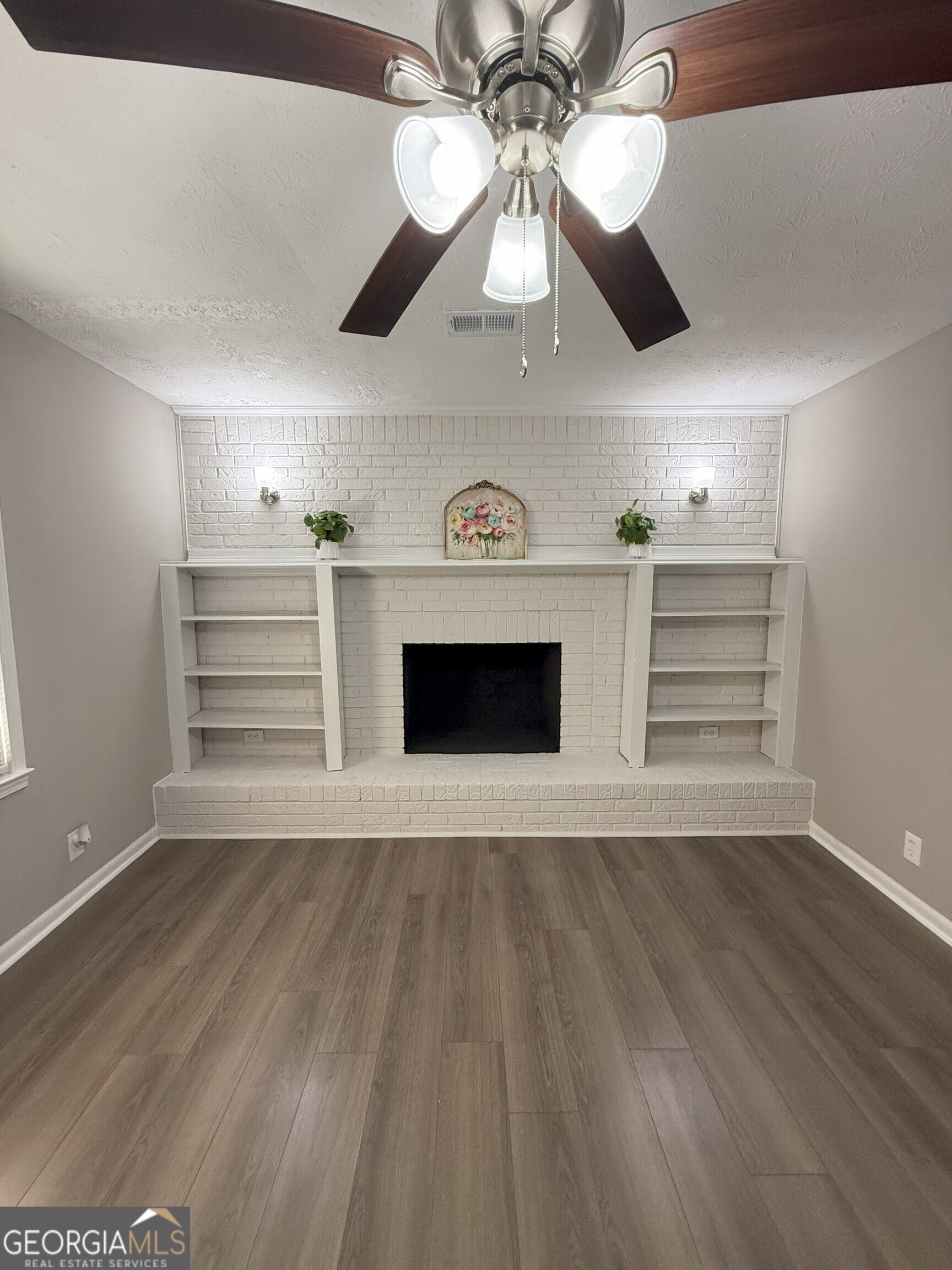 516 Harris Street Monroe, GA 30655 - Photo 3 of 25 a view of an empty room and a kitchen with wooden floor