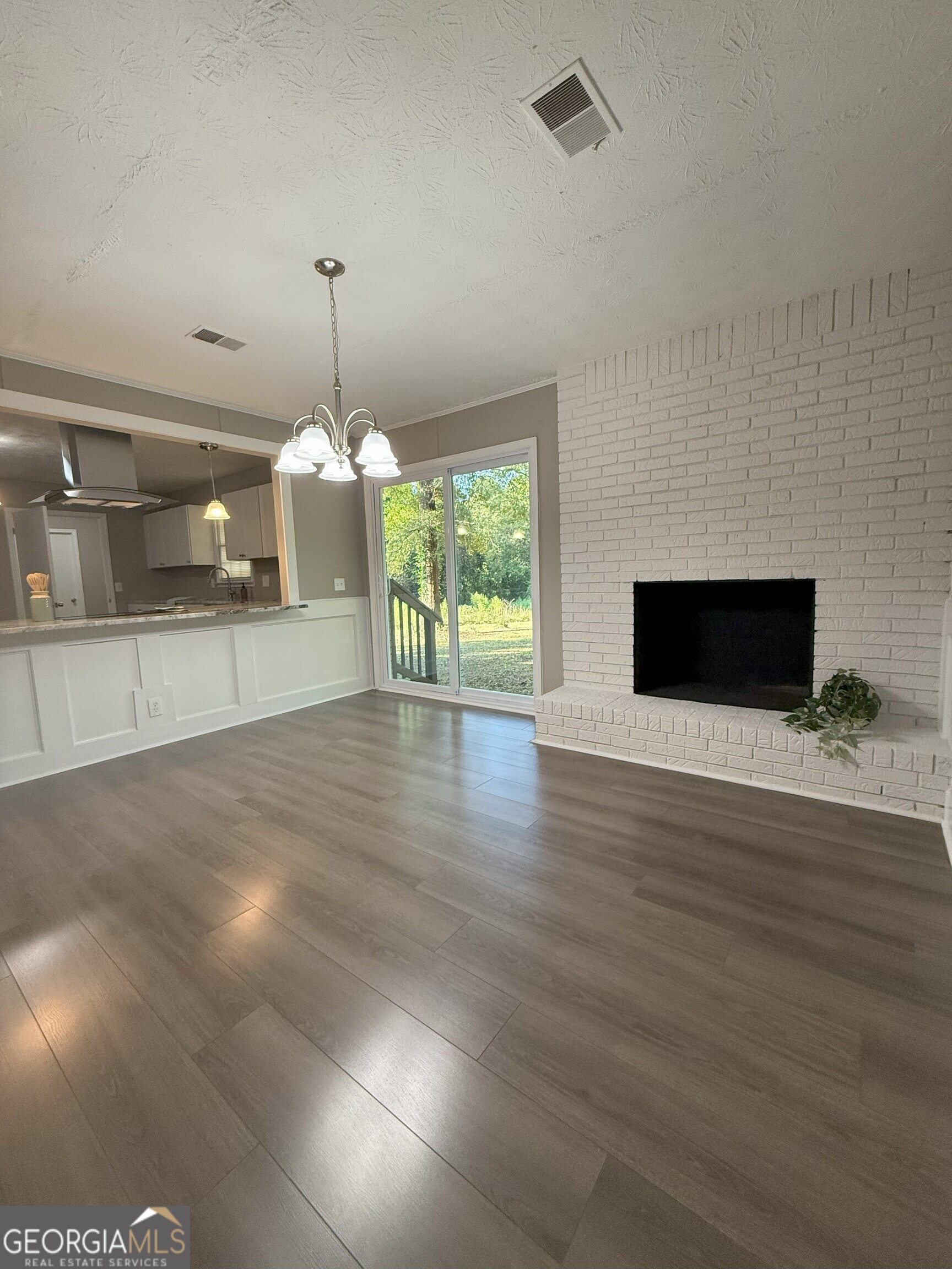 516 Harris Street Monroe, GA 30655 - Photo 8 of 25 a view of an empty room with wooden floor and a kitchen