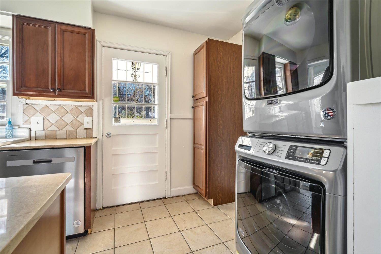 3901 Lytle Circle Memphis, TN 38122 - Photo 15 of 30 Kitchen with stainless steel dishwasher, decorative backsplash, stacked washer and dryer, and light tile patterned floors