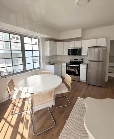 a large white kitchen with a stove a refrigerator and a dining table
