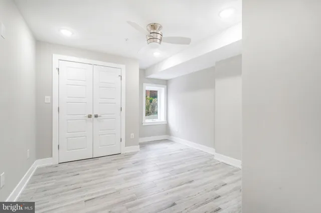 an empty room with wooden floor ceiling fan and windows