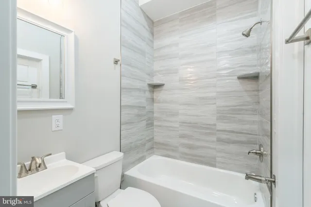 a bathroom with a bathtub shower sink vanity and toilet