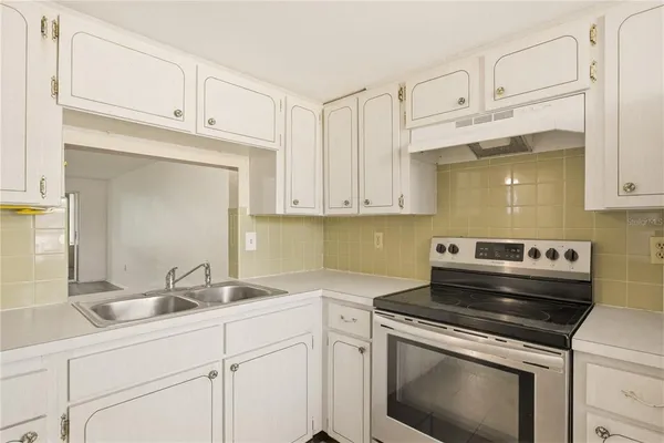 a kitchen with white cabinets and appliances