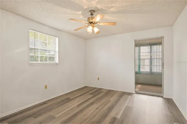 an empty room with a chandelier fan and windows