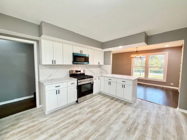 a kitchen with stainless steel appliances white cabinets a sink a stove a refrigerator and a microwave