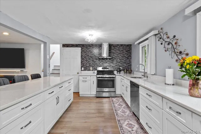 a large white kitchen with stainless steel appliances granite countertop a stove a sink and a refrigerator