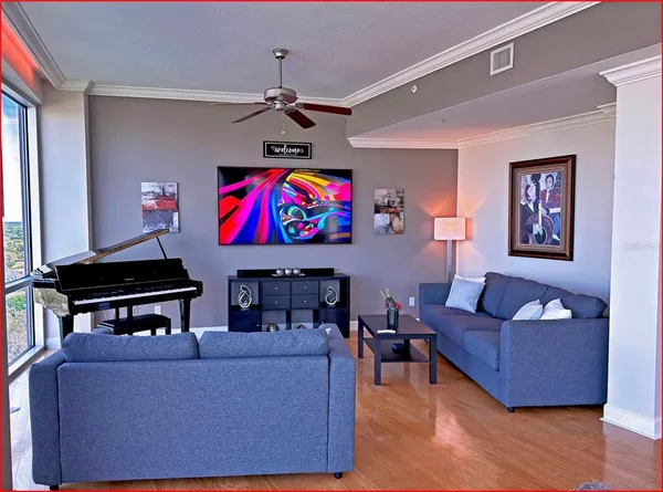 a living room with furniture and a flat screen tv with kitchen view