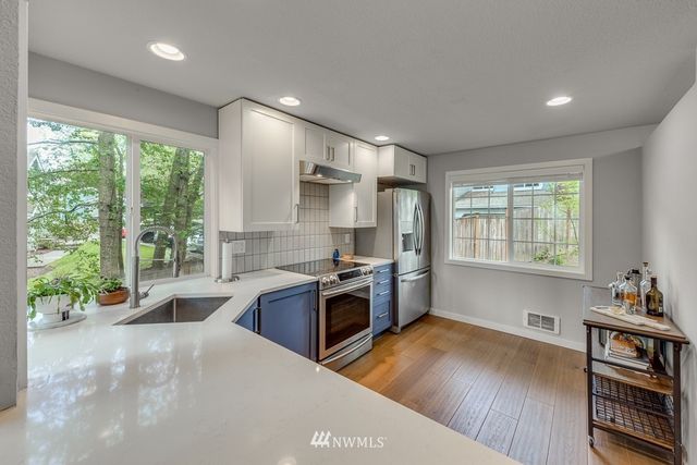 a kitchen with stainless steel appliances granite countertop a stove and a wooden floors