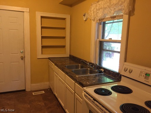 3240 Sycamore Road Cleveland, OH 44118 - Photo 4 of 7 Kitchen with dark countertops, baseboards, electric range, white cabinets, and a sink