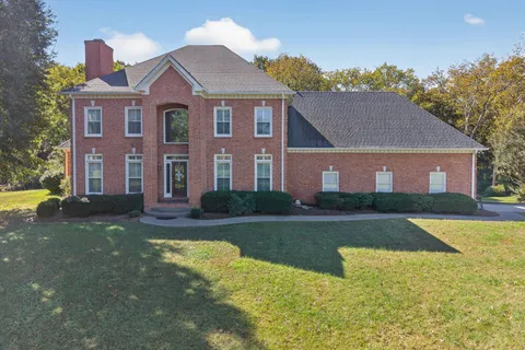a view of a brick house with a yard table and chairs