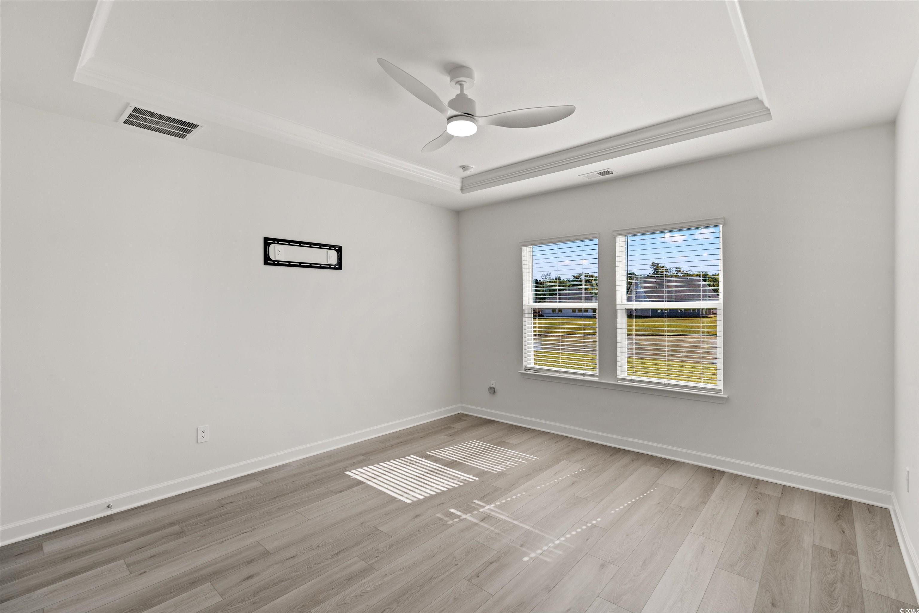 1546 Regal Fern Way Longs, SC 29568 - Photo 12 of 34 Empty room with a raised ceiling, light wood-style flooring, and a ceiling fan