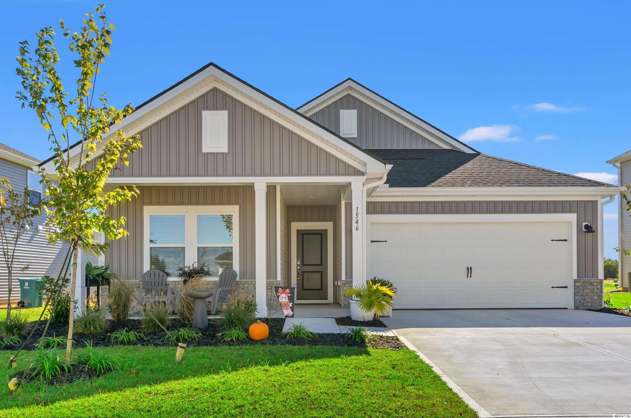1546 Regal Fern Way Longs, SC 29568 - Photo 2 of 34 Craftsman-style house featuring a porch, board and batten siding, concrete driveway, a front lawn, and an attached garage