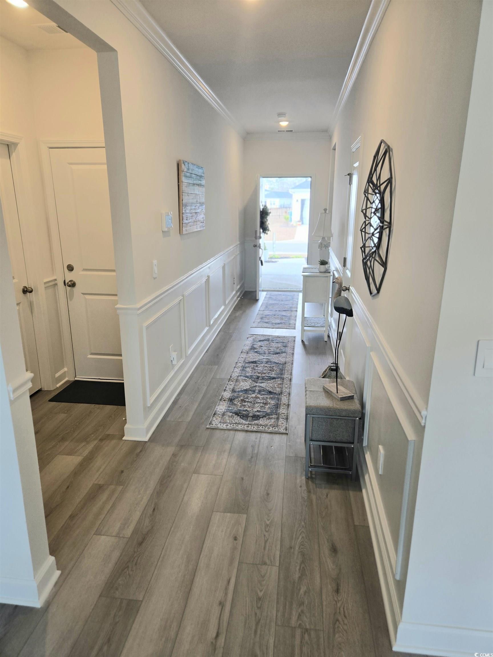 1546 Regal Fern Way Longs, SC 29568 - Photo 4 of 34 Hallway Entrance featuring a decorative wall, a wainscoted wall, ornamental molding, and dark wood-type flooring