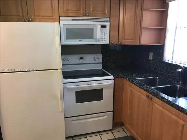 a kitchen with granite countertop a stove a sink and a microwave