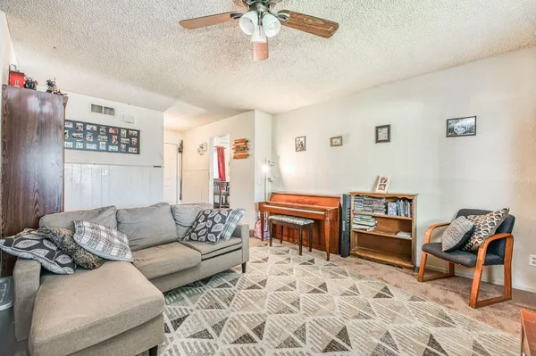 a living room with furniture a piano and a bookshelf