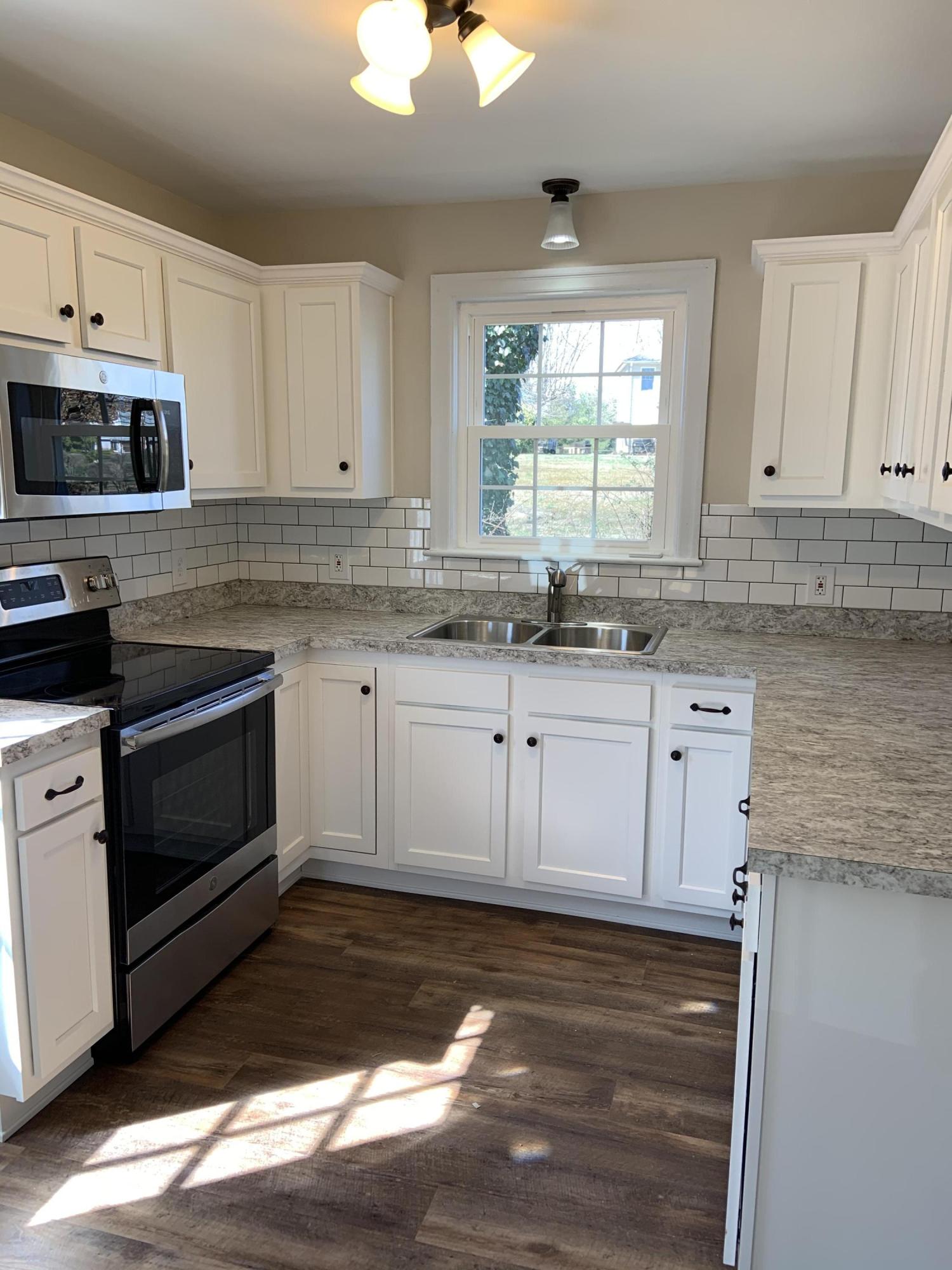 4004 Cove Road Roanoke, VA 24017 - Photo 11 of 30 a kitchen with granite countertop white cabinets white appliances a sink and a window