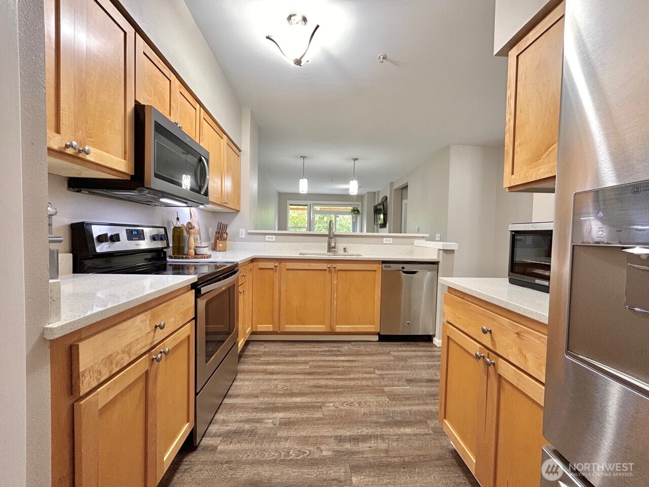 2009 196th Street Southeast, Unit A203 Bothell, WA 98012 - Photo 7 of 19 a kitchen with stainless steel appliances granite countertop a stove top oven a sink dishwasher and a refrigerator with wooden floor