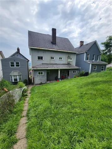 a view of a house with a big yard and large trees