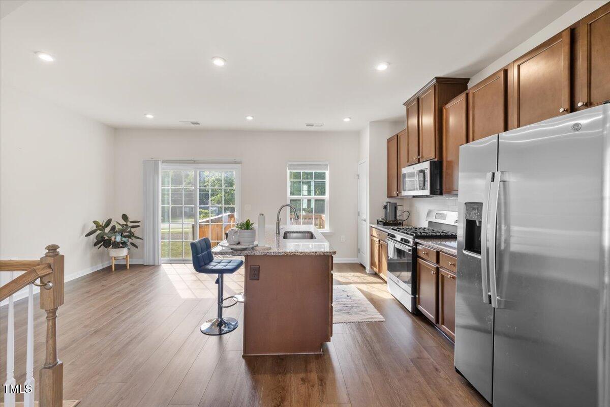 6620 Pathfinder Way Raleigh, NC 27616 - Photo 13 of 39 a kitchen with stainless steel appliances a dining table wooden floor and a large window