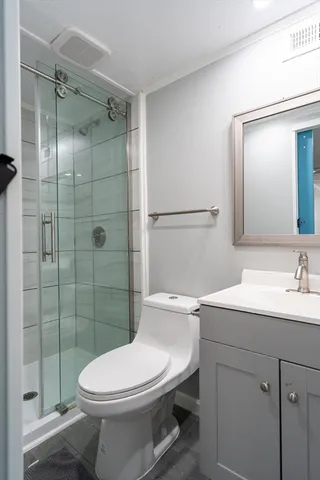 a bathroom with a toilet sink vanity and shower