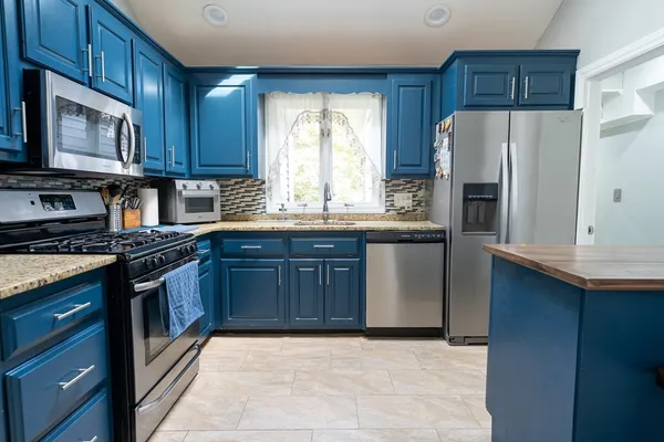 a kitchen with stainless steel appliances granite countertop a stove a refrigerator and a microwave