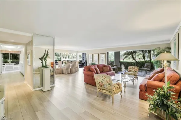a living room with furniture a large window and wooden floor
