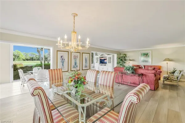 a view of a dining room with furniture a chandelier and large windows