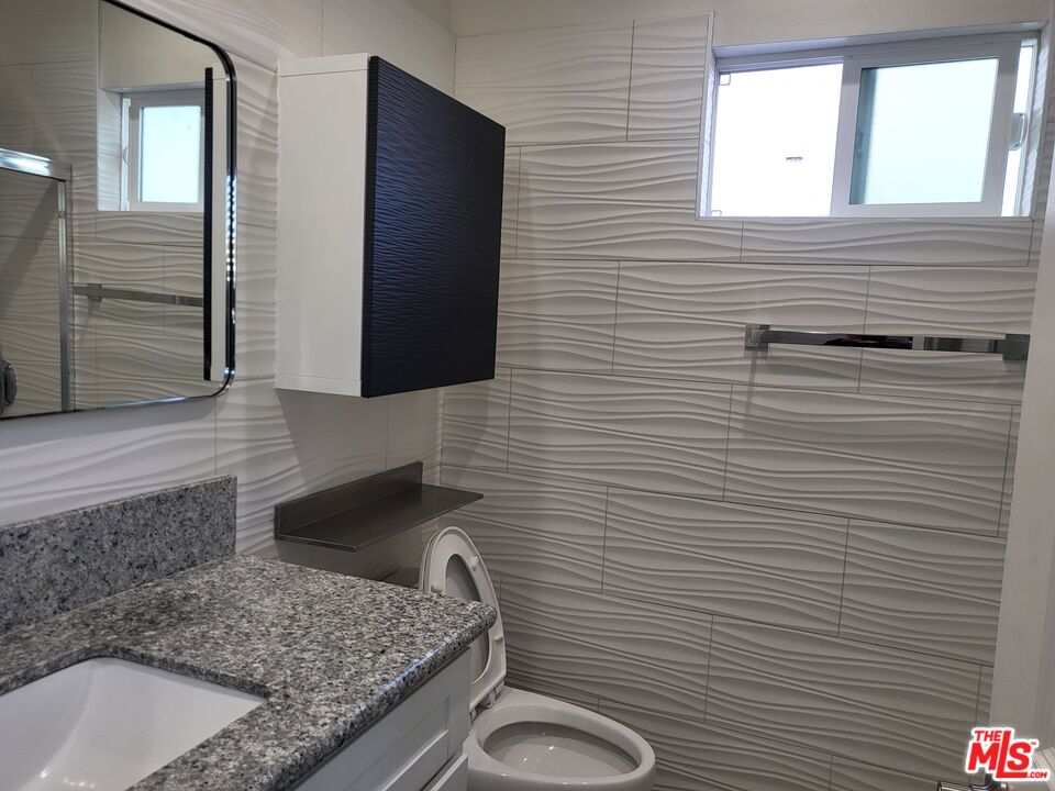 2754 West 12th Street Los Angeles, CA 90006 - Photo 11 of 17 a bathroom with a granite countertop toilet sink and mirror