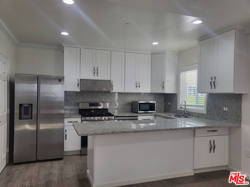 2754 West 12th Street Los Angeles, CA 90006 - Photo 2 of 17 a kitchen with granite countertop a refrigerator a sink a stove a microwave and island