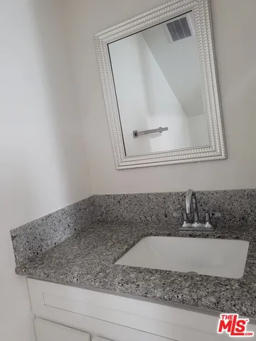 a bathroom with a granite countertop sink and a mirror