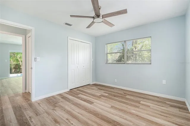a view of empty room with wooden floor and fan