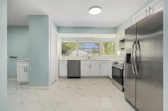a large white kitchen with a sink stainless steel appliances and cabinets