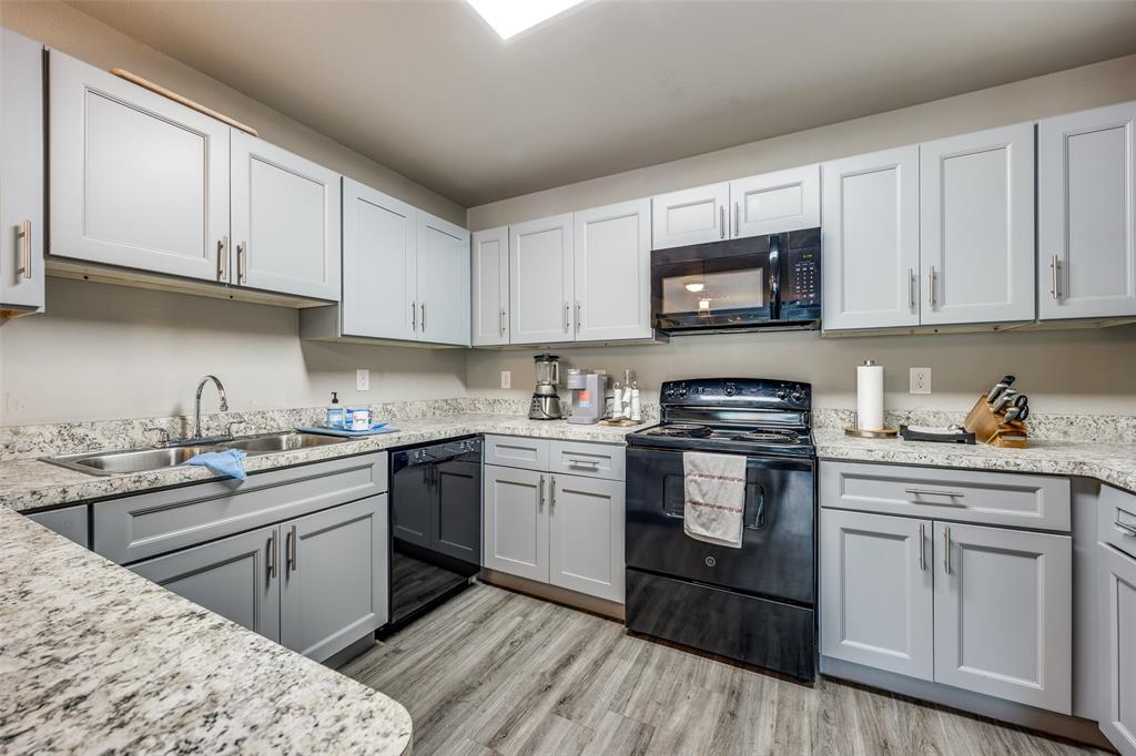 6108 Abrams Road, Unit 205 Dallas, TX 75231 - Photo 7 of 12 Kitchen with black appliances, light wood finished floors, and light stone countertops