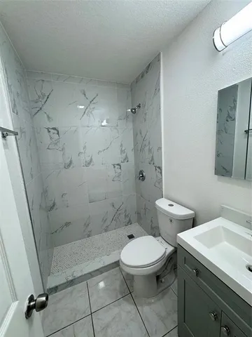 a bathroom with a toilet a sink a shower and a mirror