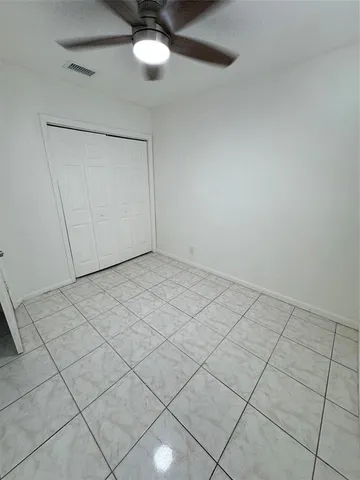 a view of an empty room and chandelier fan