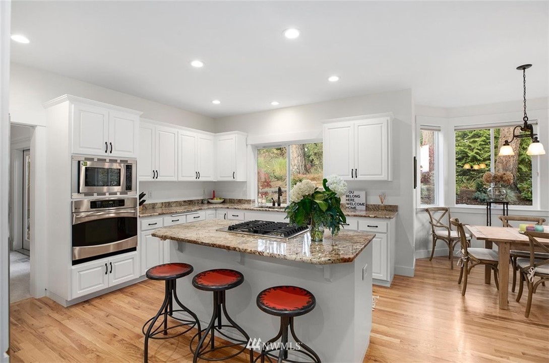 18906 Ross Road Bothell, WA 98011 - Photo 9 of 34 a kitchen with stainless steel appliances granite countertop a stove a sink a oven a dining table and chairs with wooden floor