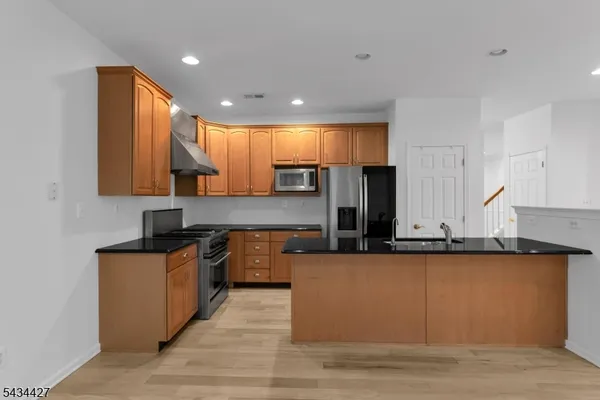 a kitchen with stainless steel appliances granite countertop a sink a stove counter space and cabinets
