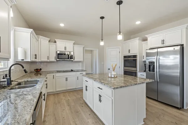 a kitchen with stainless steel appliances granite countertop a sink refrigerator and cabinets