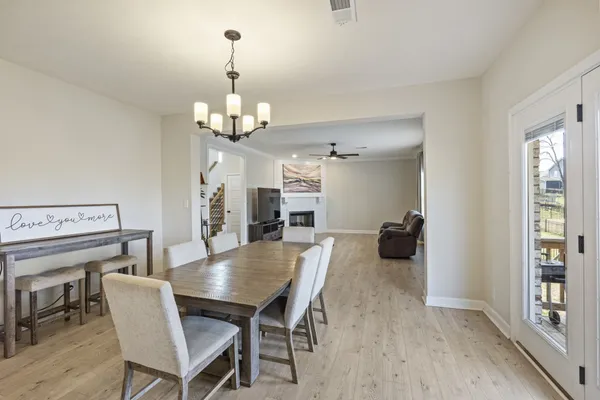 a dining room with wooden floor a chandelier a wooden table and chairs