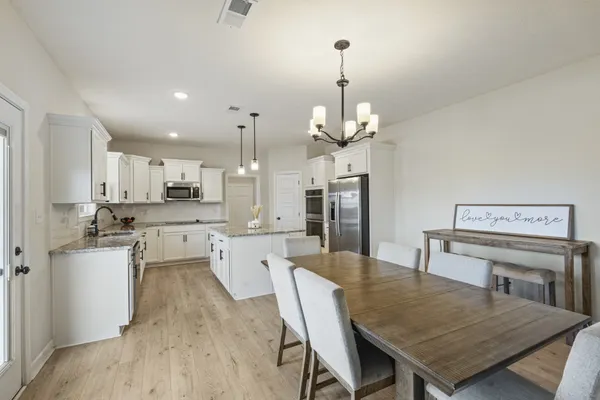 a kitchen with stainless steel appliances a dining table chairs stove and refrigerator