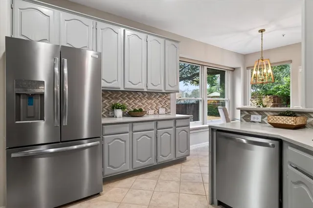 a kitchen with stainless steel appliances granite countertop a refrigerator a sink a stove and a window