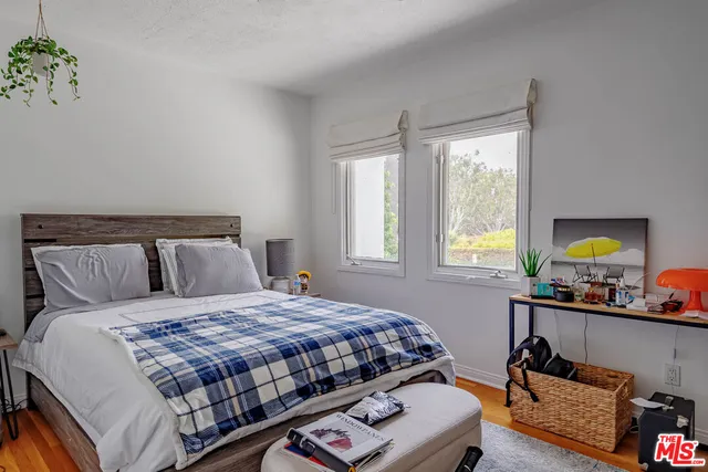 a bedroom with a bed table chair and a window