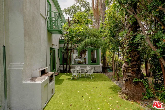 a view of a patio with table and chairs potted plants and large tree