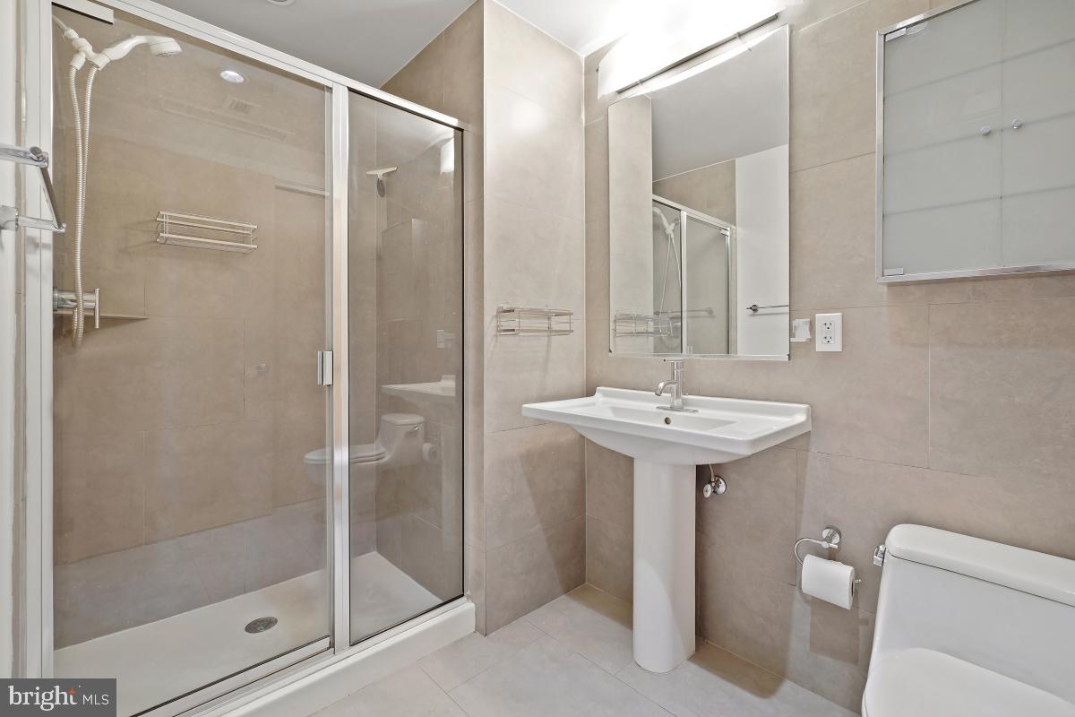1133 14th Street Northwest, Unit 1103 Washington, DC 20005 - Photo 21 of 39 a bathroom with a shower sink mirror and toilet