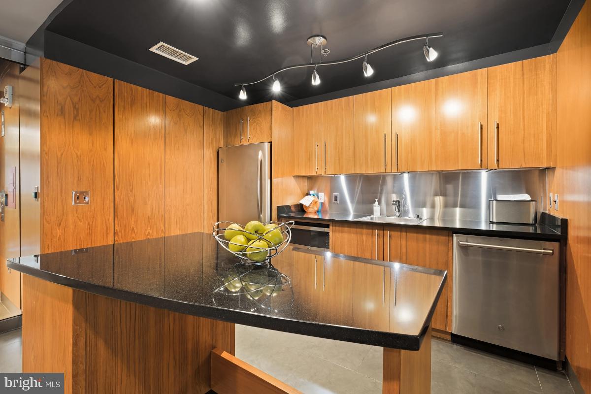 1133 14th Street Northwest, Unit 1103 Washington, DC 20005 - Photo 30 of 39 a kitchen with stainless steel appliances granite countertop a sink a stove and a refrigerator